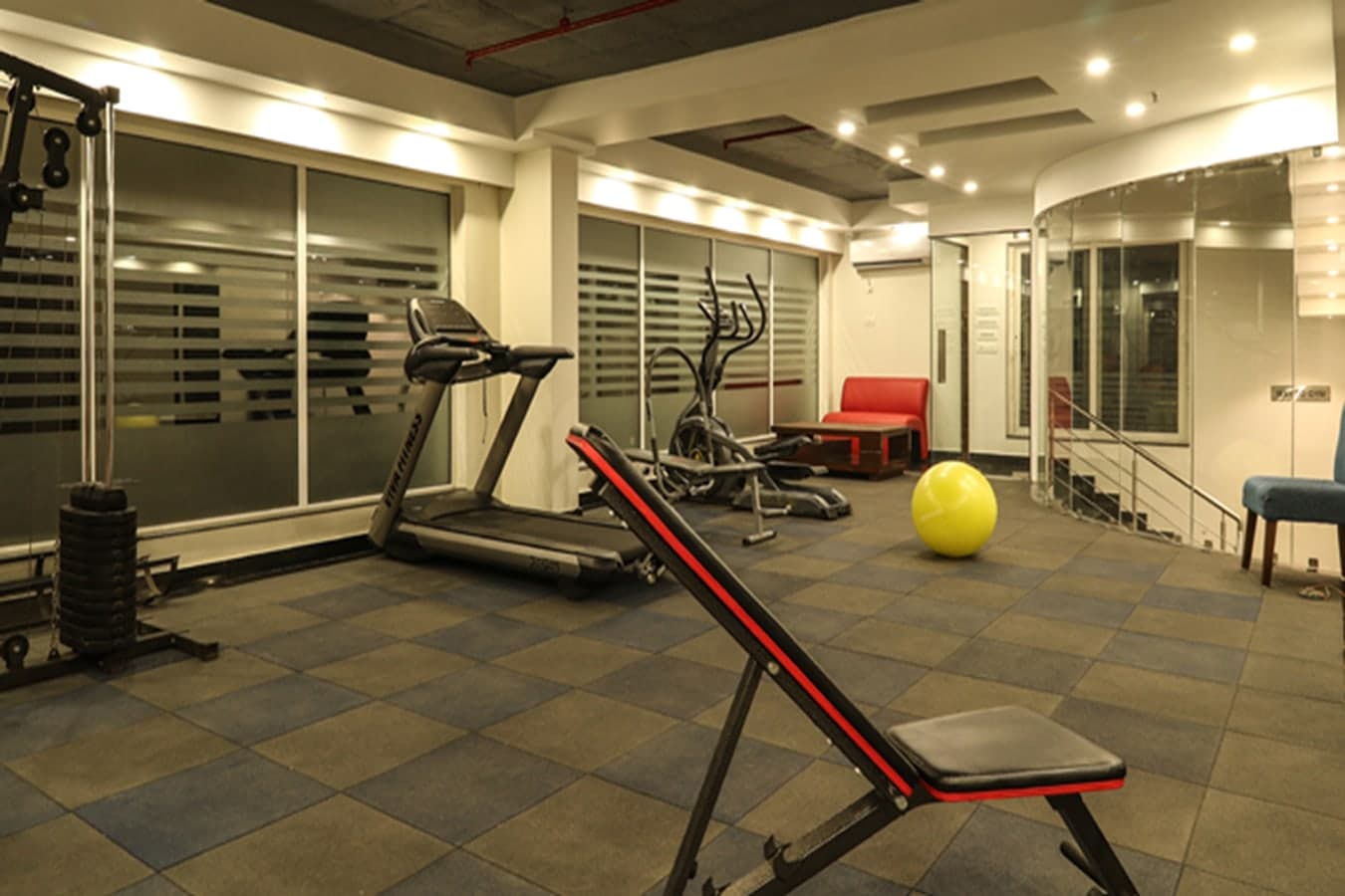 Hotel gym with a treadmill, weight bench, cable machine and exercise ball
