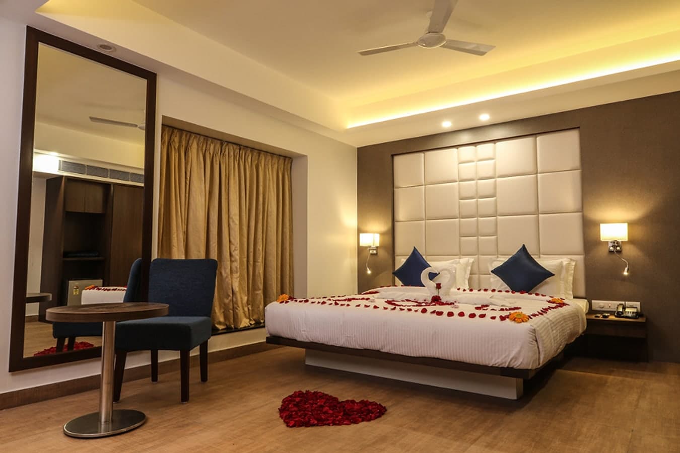 King bed decorated with rose petals and towel swans for a honeymoon stay
