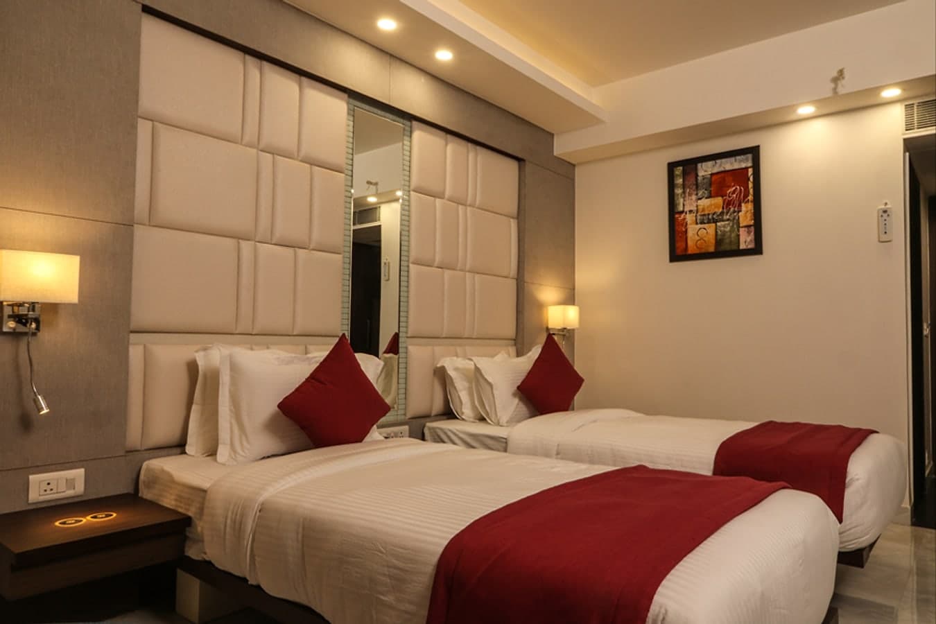 Luxury Twin room with two single beds, red throws and a padded headboard wall