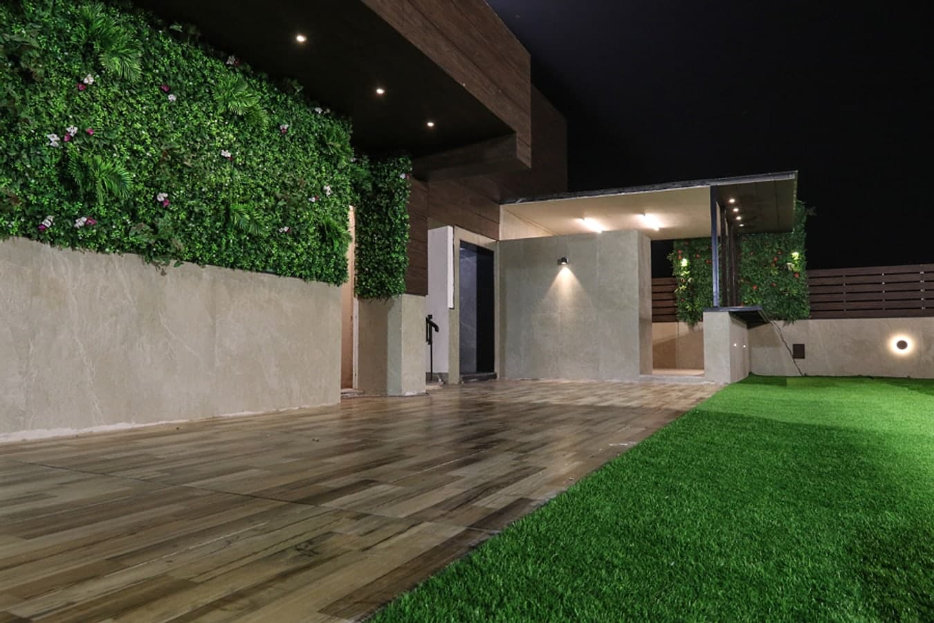 Sky-View rooftop at night with a flowering living wall, wooden deck and lawn