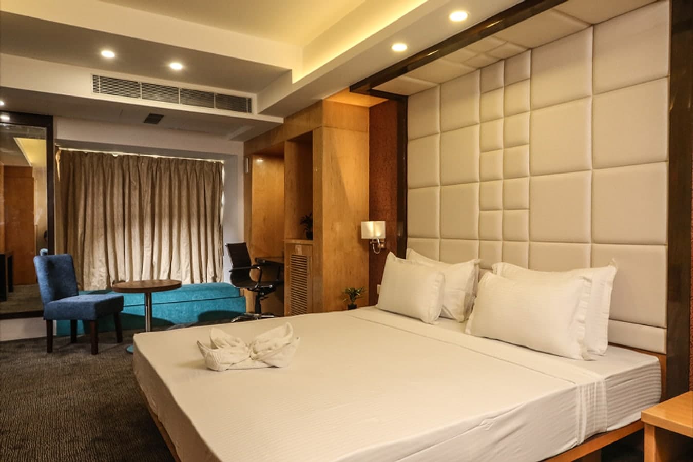 Suite bedroom with a king bed, tall padded headboard and a separate seating area