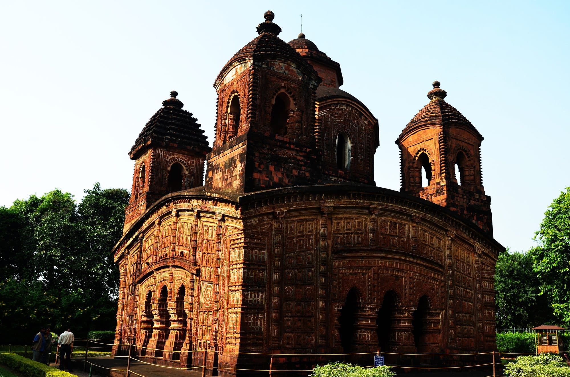 The Shyam Rai terracotta temple in Bishnupur, its carved brick walls glowing red under a clear sky