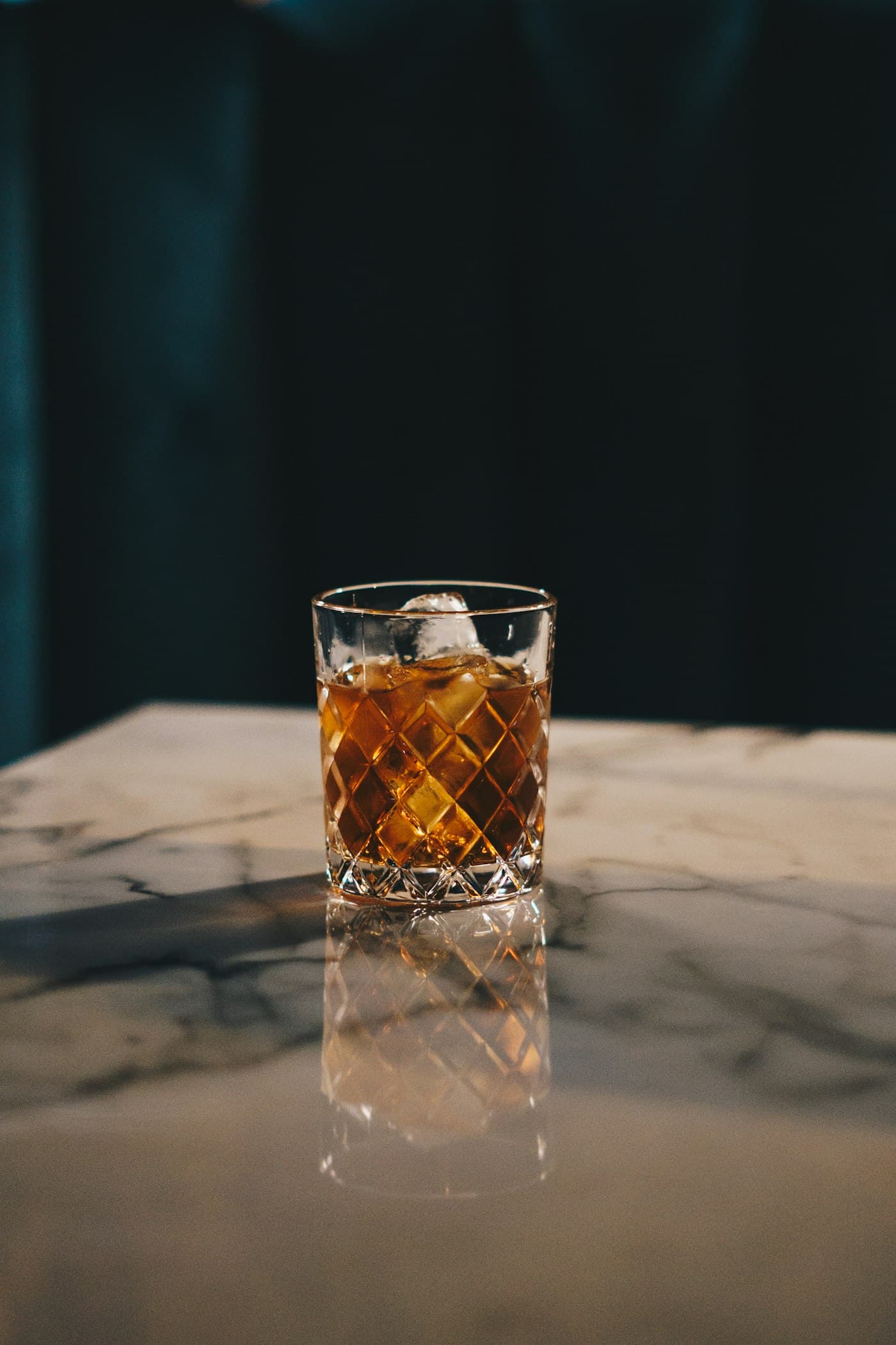 Whisky in a cut-crystal glass on a marble bar counter in low light