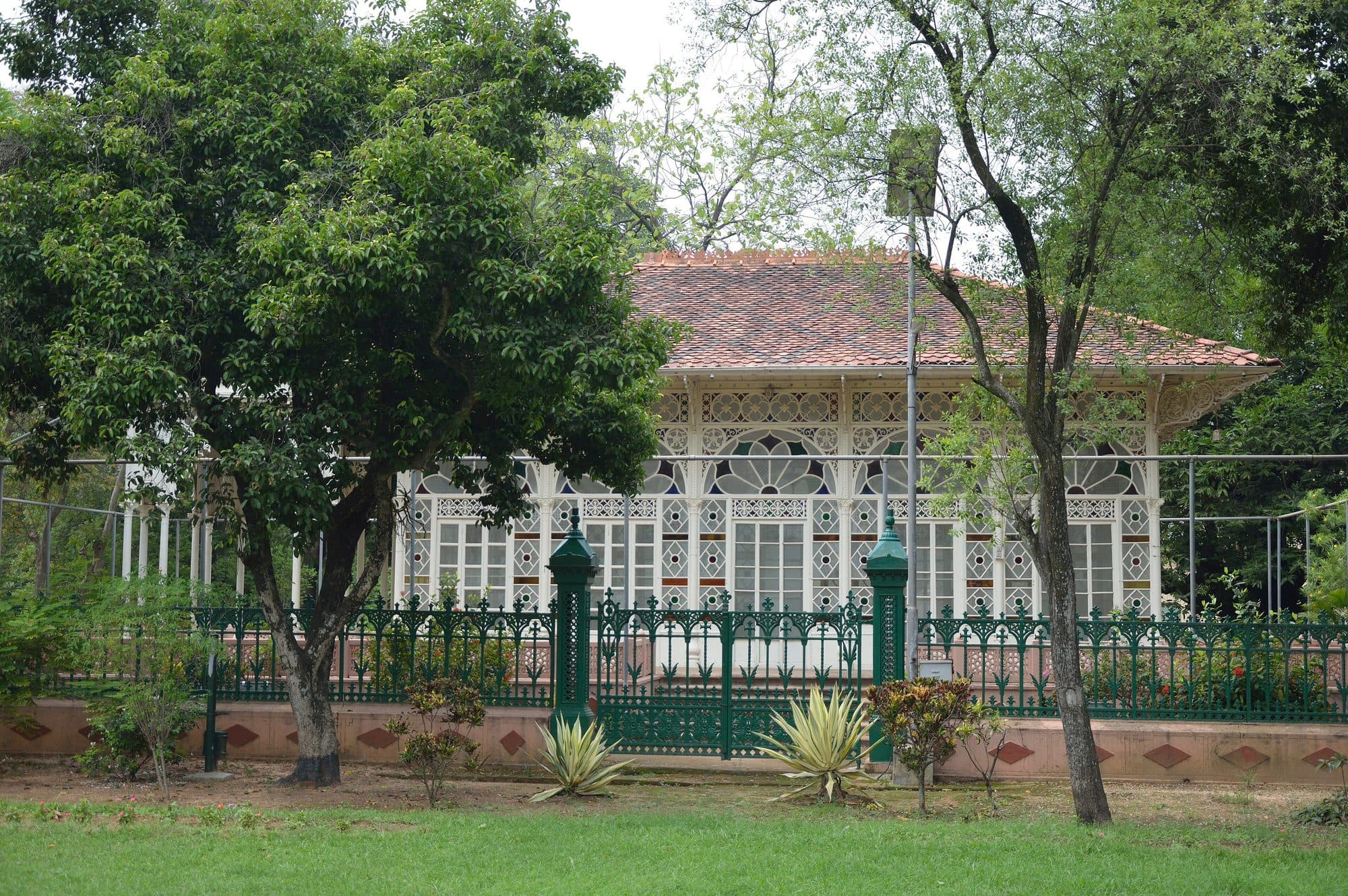 Upasana Griha in Santiniketan, a prayer hall of white iron lacework and coloured glass behind a green railing
