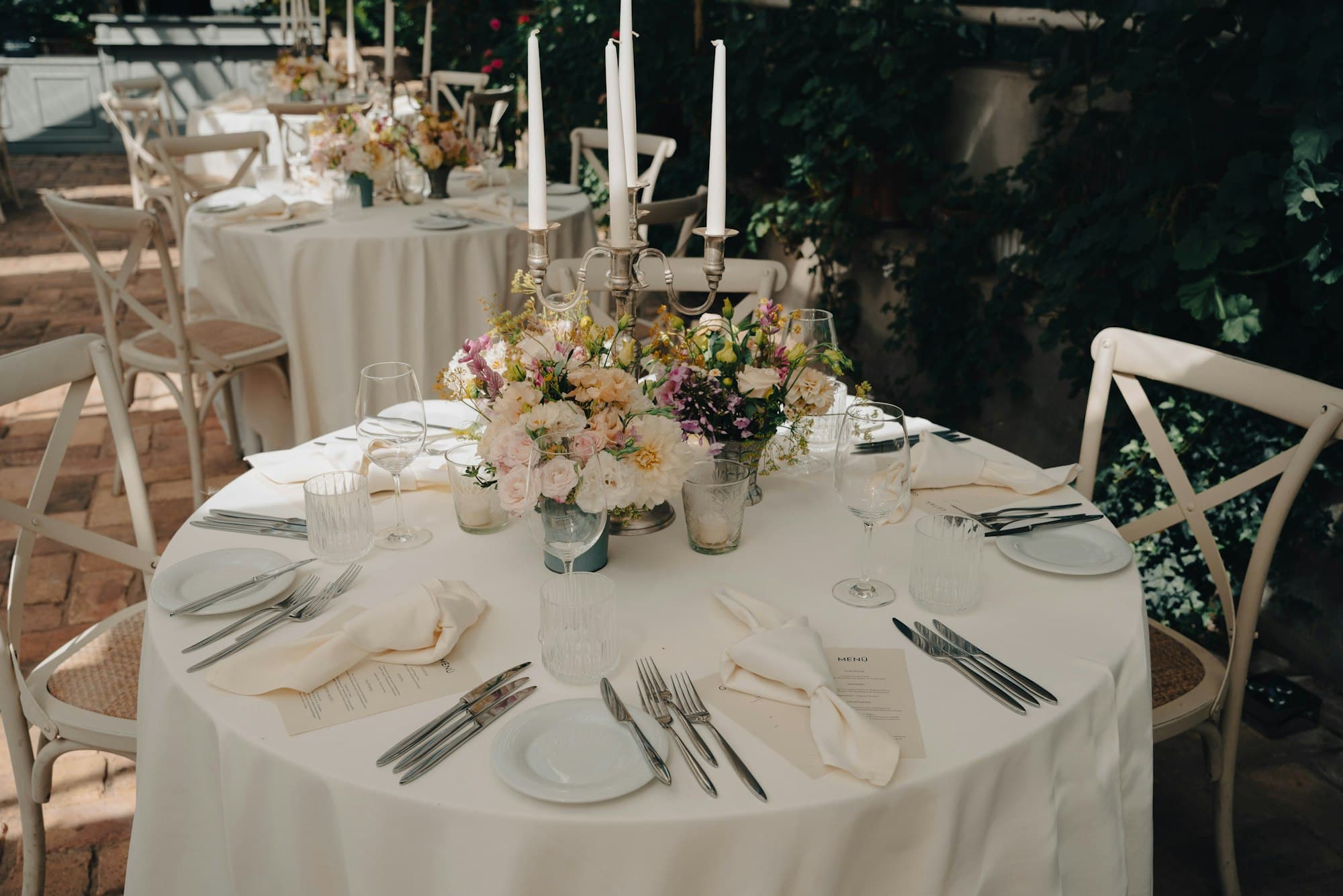 A round table dressed with white linen, candles and fresh flowers